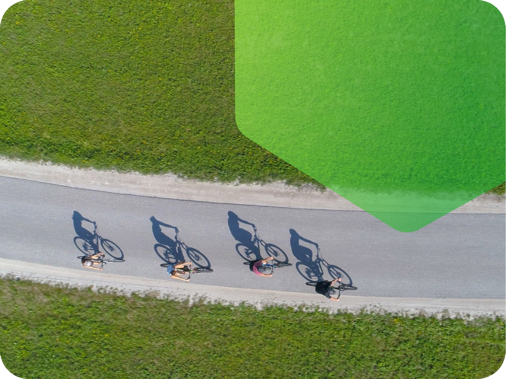 Cyclists on a road surrounded by grass on a sunny day